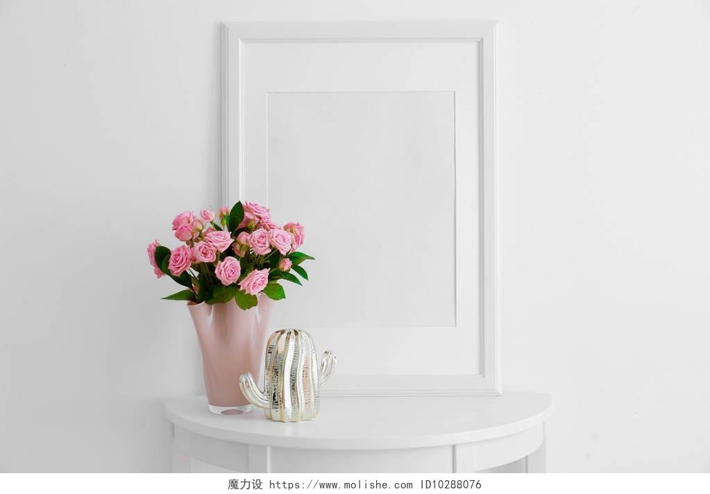 粉红色的玫瑰和装饰仙人掌雕像在桌子附近的白墙